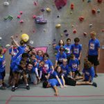 group of kids posing inside an indoor climbing gym with their instructor